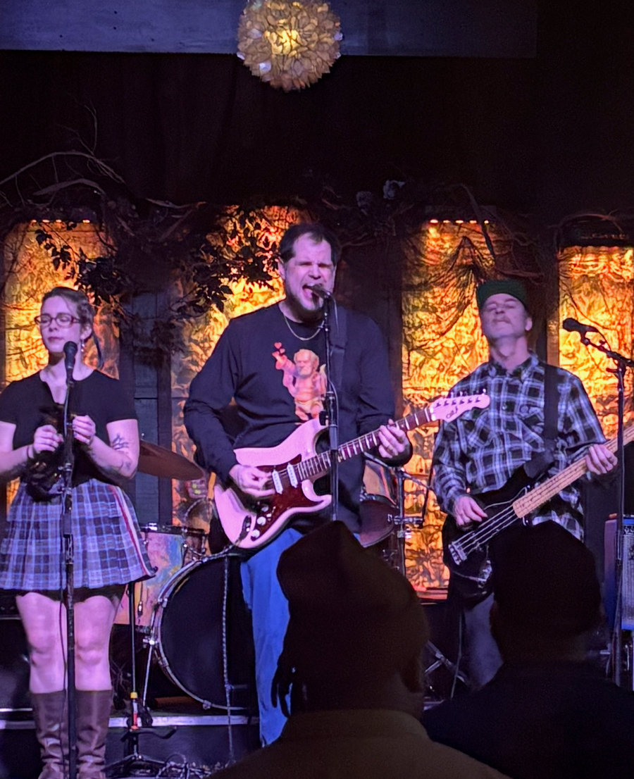Band playing on stage with lead singer wearing Boozie Adams Cupid Tee
